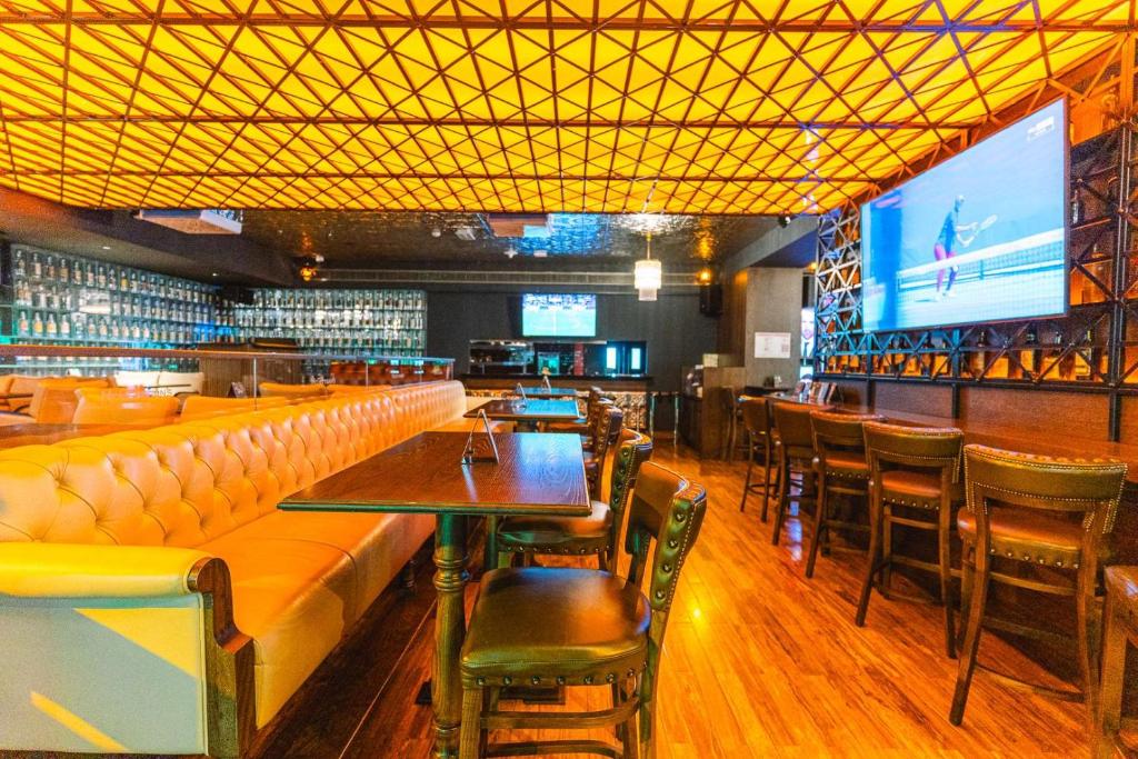 a bar with tables and chairs and a large screen at Dusit Thani Abu Dhabi in Abu Dhabi