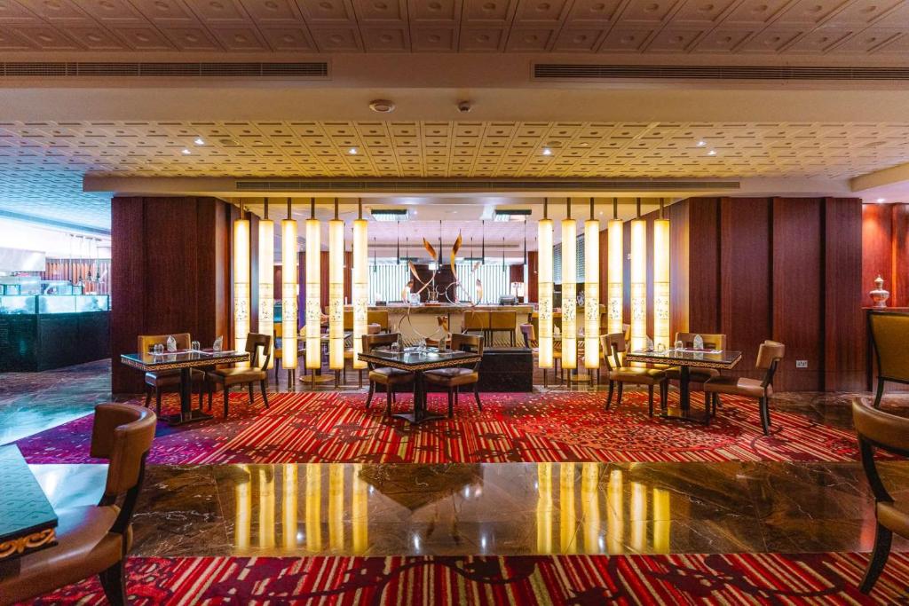a restaurant with tables and chairs in a room at Dusit Thani Abu Dhabi in Abu Dhabi
