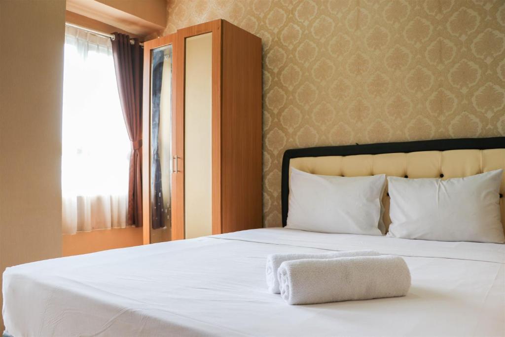 a bedroom with a white bed with a towel on it at Modern and Nice Studio at Titanium Square Apartment By Travelio in Jakarta
