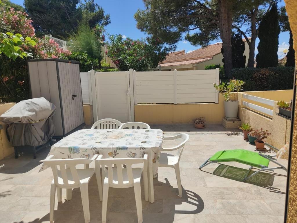 une table blanche et des chaises sur une terrasse dans l'établissement Appartement T2 Climatisé à Gruissan - Piscine, Plage, Parking & Terrasse - Idéal Familles 4/5 pers. - FR-1-796-45, à Gruissan