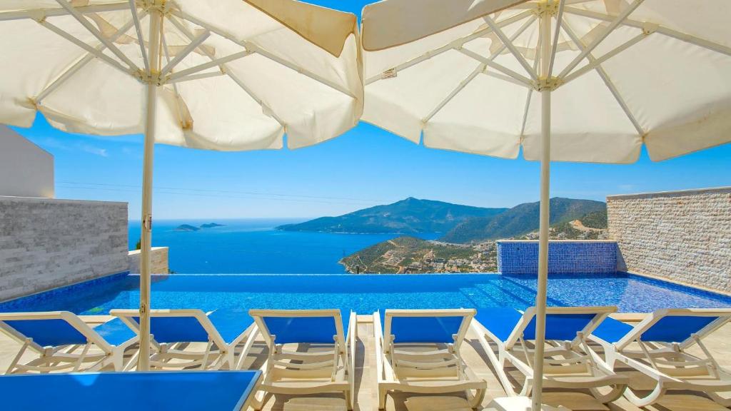 a group of chairs and umbrellas on a swimming pool at Kalkan 3 Bedroom Seaview Luxury Villa - Heated Indoor Pool in Kalkan
