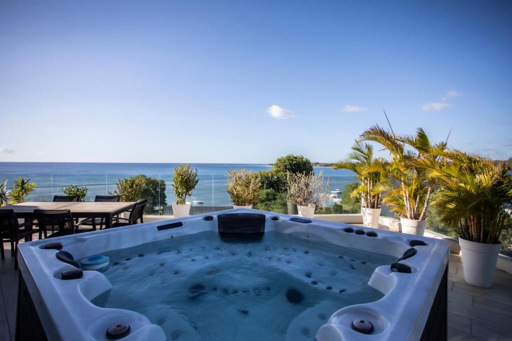 a hot tub on a patio with a view of the ocean at Modern Penthouse - Sunset, Jacuzzi & Sea Views in Tamarin