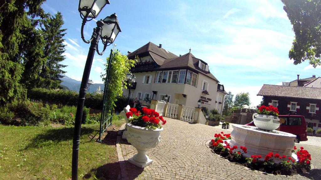 a street light with two vases of flowers in front of a house at Hotel Post Victoria in Soprabolzano