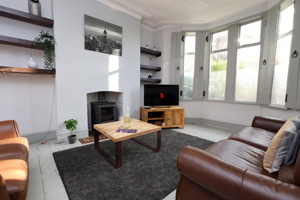 a living room with a couch and a table and a television at Central Cardiff Victorian Town House Free parking in Cardiff