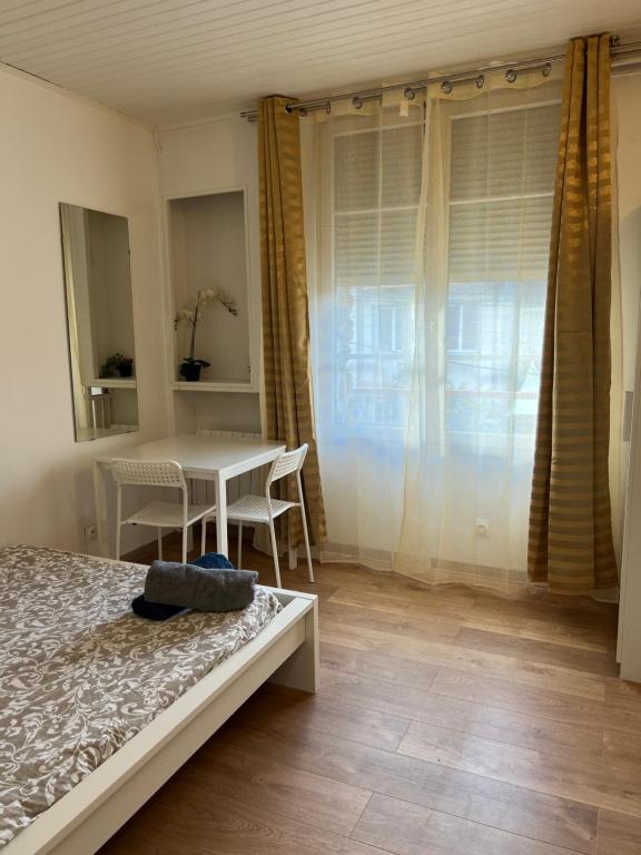 ein Schlafzimmer mit einem Bett und einem Tisch und einem Fenster in der Unterkunft Rosny Sous Bois centre ville charmant appartement in Rosny-sous-Bois