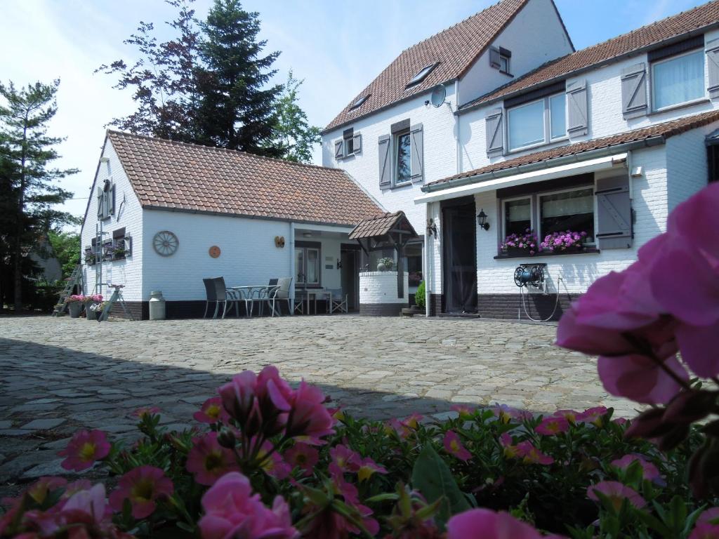una casa con patio y flores en el primer plano en B&B De Kroonhoeve en Beringen