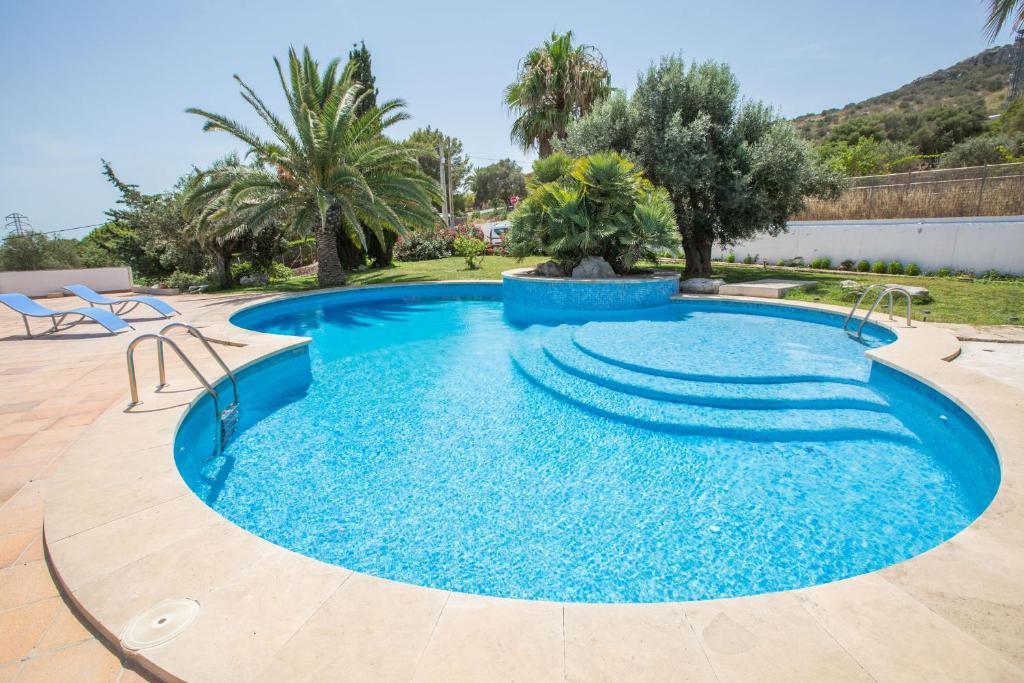 een zwembad met blauw water in een tuin met palmbomen bij Na Penyal in Cala Millor