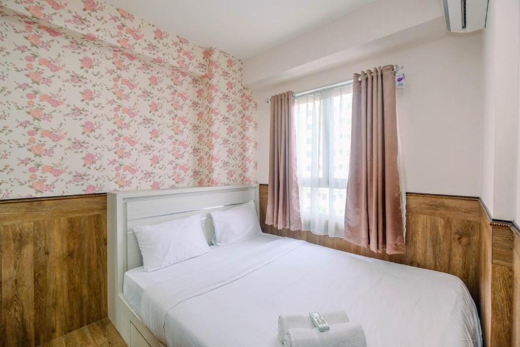 a small bedroom with a bed and a window at Minimalist and Comfy 2BR at Titanium Square Apartment By Travelio in Jakarta