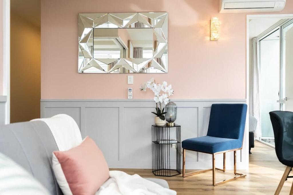 a living room with a blue chair and a mirror at Tasteful Luxury Modern 2BR with Aircon in the City Next to Albert Park in Auckland