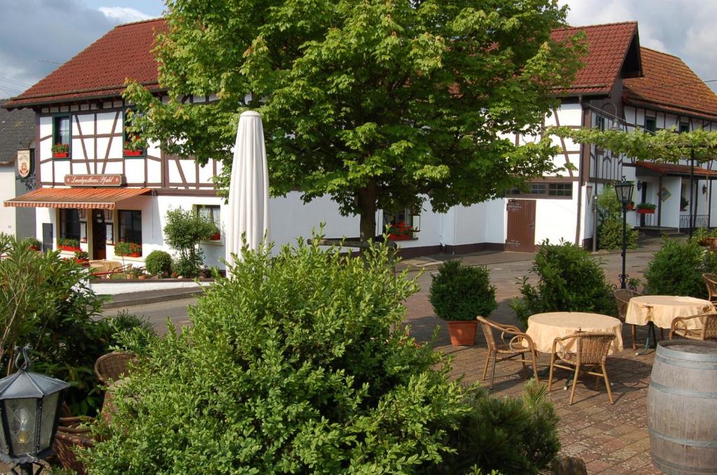 ein weißes Gebäude mit einem Tisch und einem weißen Regenschirm in der Unterkunft Landgasthaus Pfahl in Wershofen