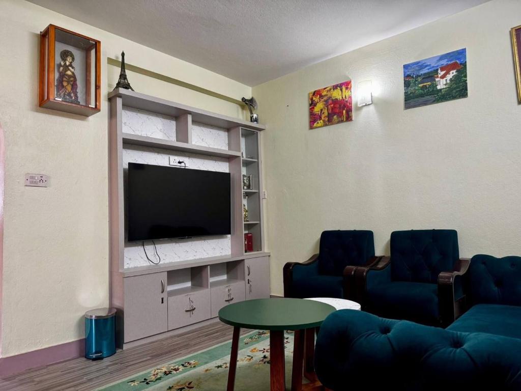 a living room with two blue chairs and a flat screen tv at Private Couple Apartment in Kathmandu