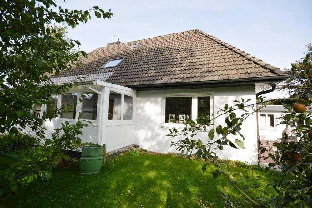 a white house with a door and a yard at Ferienhaus-Ankerplatz in Norden