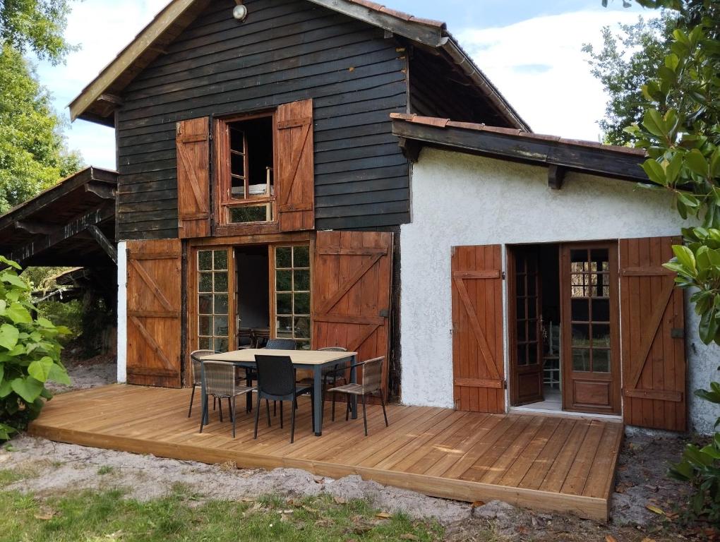 une maison avec une terrasse en bois et une table sur celle-ci dans l'établissement grange aménagée, à Mimizan
