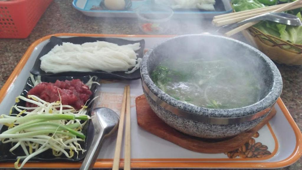a tray of food with a bowl and vegetables on it at Sao Khue 2 Hotel in Buon Ma Thuot