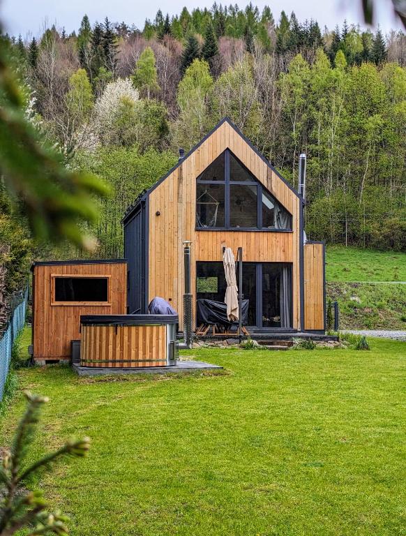 a wooden house in a field of green grass at Babia Ostoja - domek z balią i sauną in Zawoja