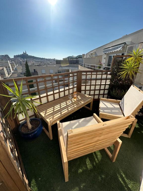 d'un balcon avec des tables et des chaises en bois sur le toit. dans l'établissement Stunning rooftop, near Cours Julien, à Marseille