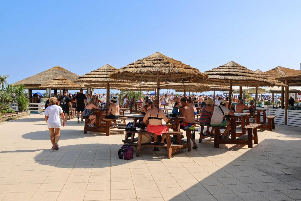 a group of people sitting at tables under umbrellas at Camping Village Capalonga in Bibione