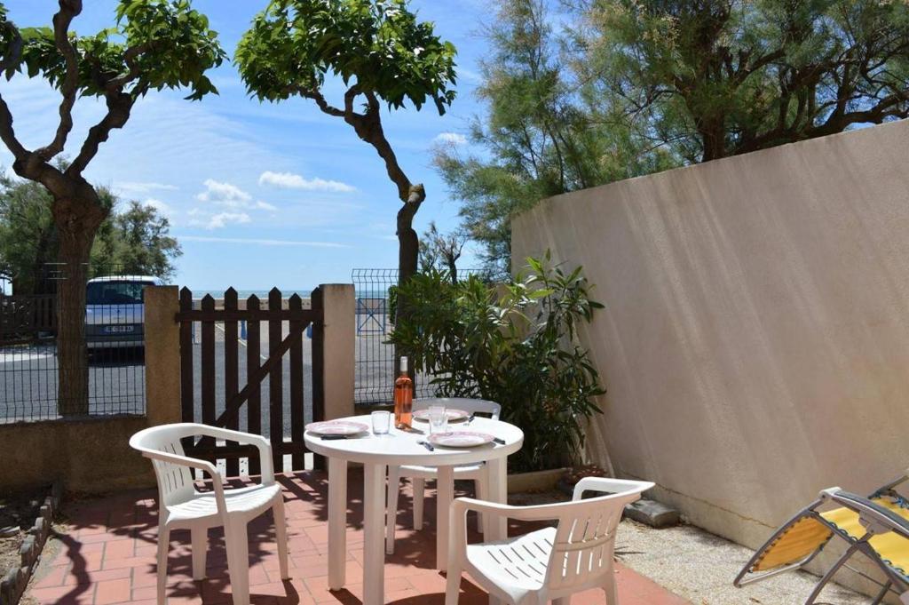 une table et des chaises sur une terrasse avec une clôture dans l'établissement SP000-048 Appt 3 pièces 4 couchages SAINT PIERRE LA MER, à Saint Pierre La Mer