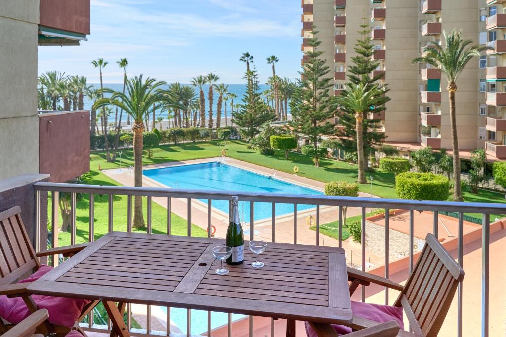 アルムニェーカルにあるApartamento Son De Mar Gondolasのプール付きのバルコニーにテーブルとワイングラスを用意しています。