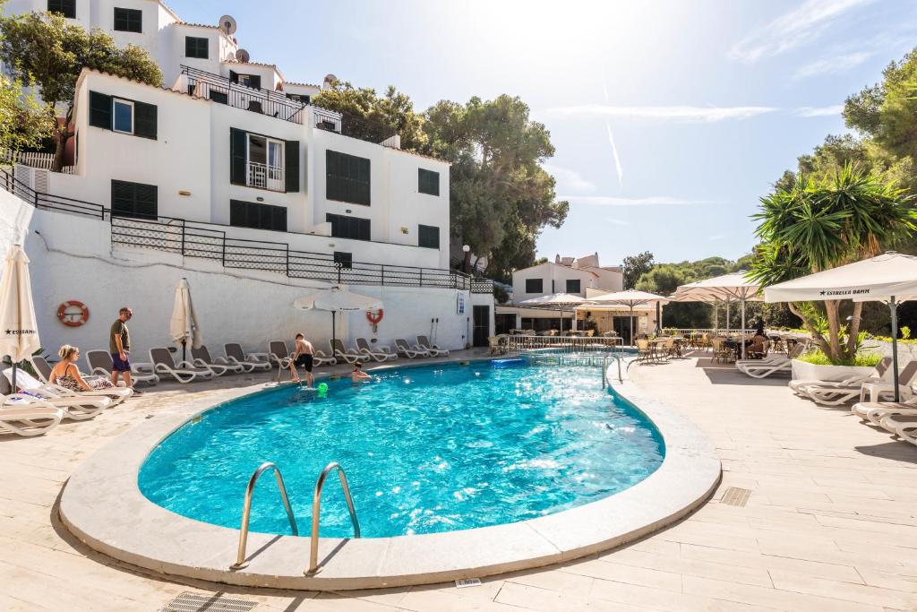 a swimming pool in front of a hotel at Apartamentos Alta Galdana in Cala Galdana