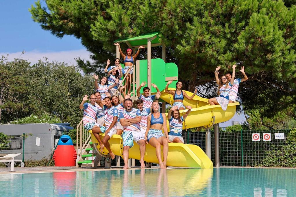 a group of people sitting on a yellow slide in a pool at Camping Lido in Bibione