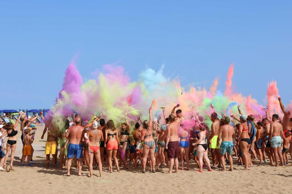 a group of people standing on the beach with colored smoke at Camping Lido in Bibione