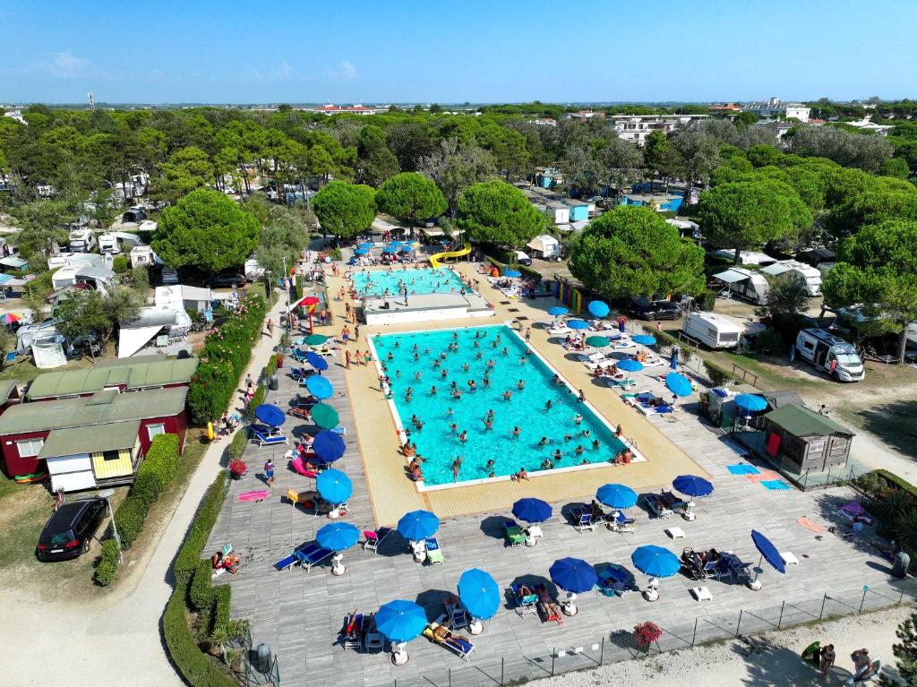 an overhead view of a swimming pool with people in chairs and umbrellas at Camping Lido in Bibione