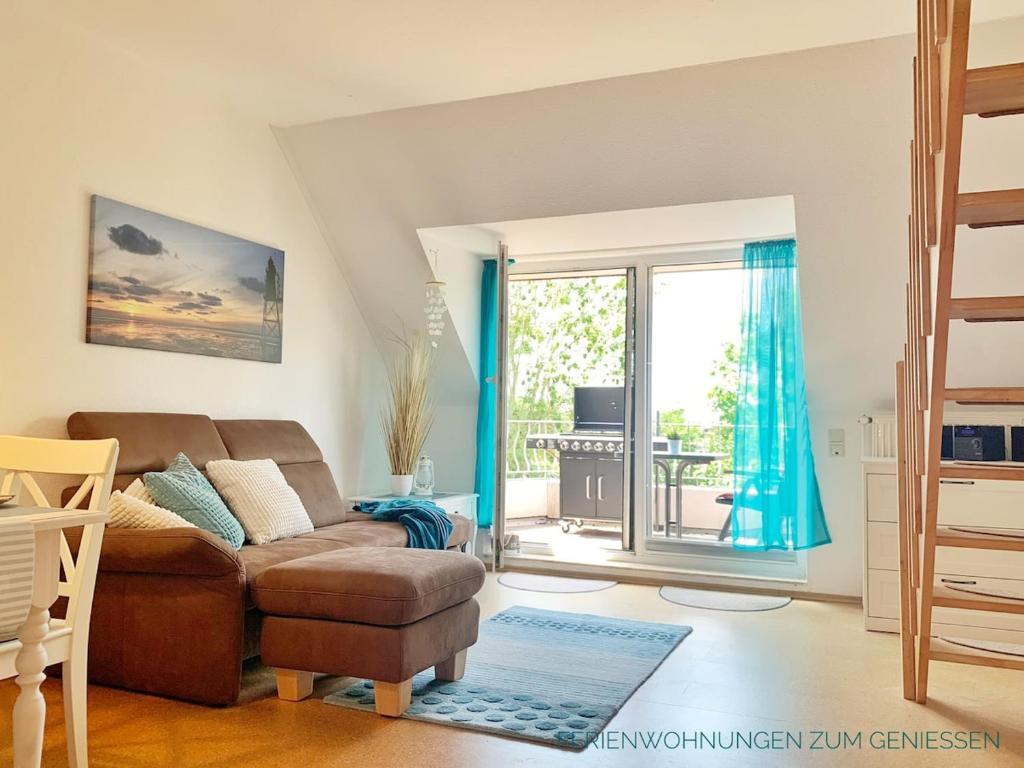 un soggiorno con un divano e una porta scorrevole in vetro di Ferienwohnung Boje 9 mit Sauna a Dorum-Neufeld