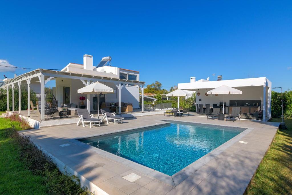 a villa with a swimming pool in front of a house at Casa Bianca Villa in Kolimbia