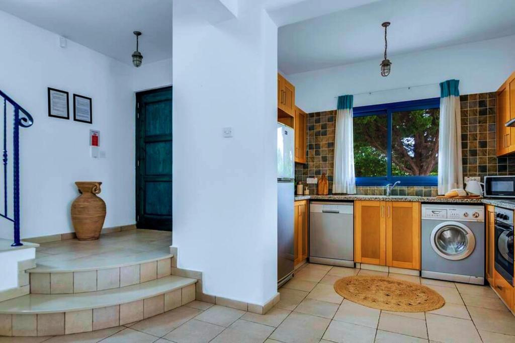 a kitchen with a washer and a washing machine at Azzurro Holiday Villas in Peyia