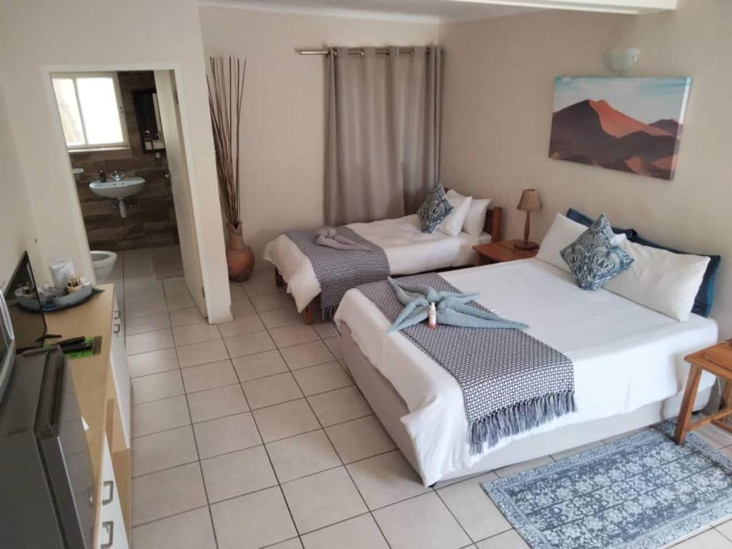 a hotel room with two beds and a bathroom at The Mole Guesthouse in Swakopmund