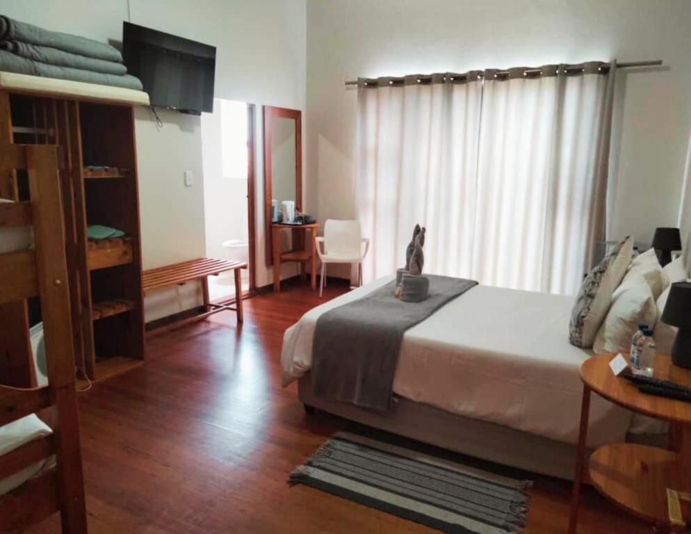 a bedroom with a bed and a desk and a window at The Mole Guesthouse in Swakopmund