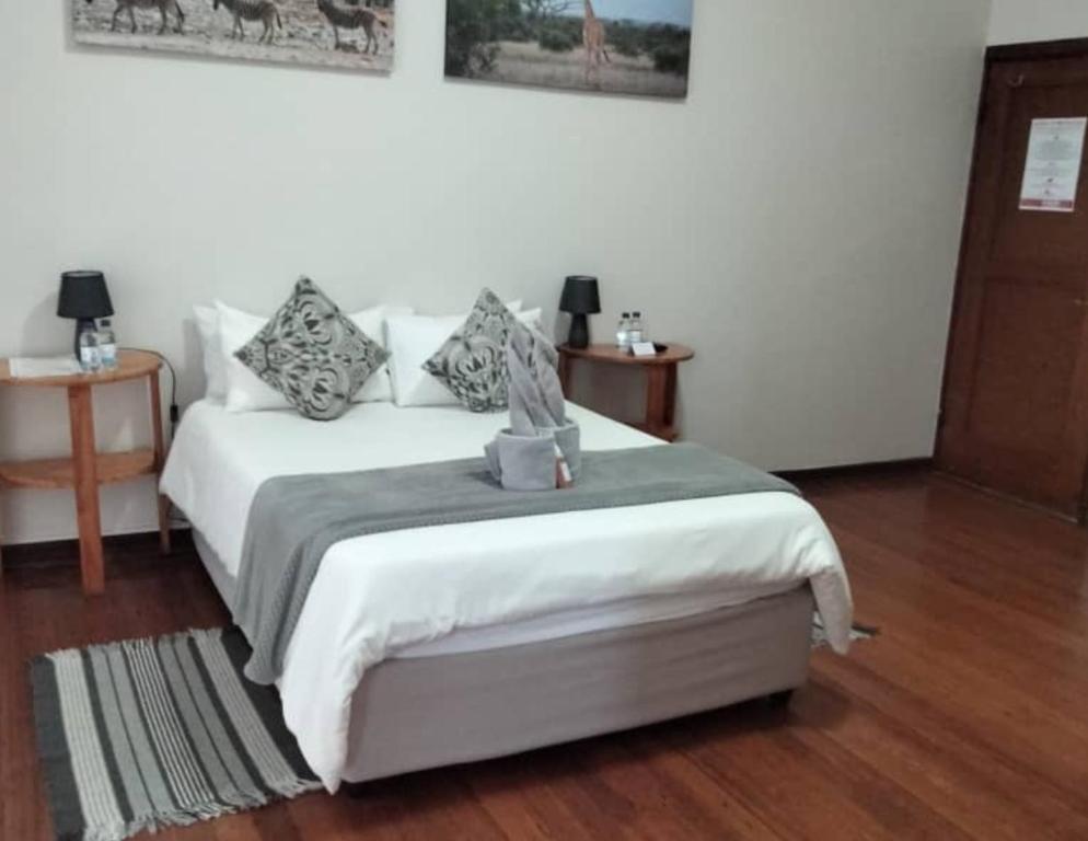 a bedroom with a white bed and two night stands at The Mole Guesthouse in Swakopmund