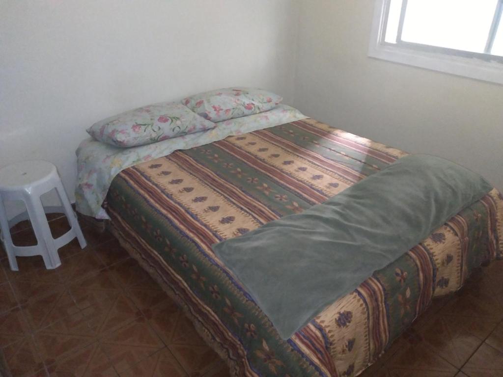 a small bedroom with a bed with a quilt at excelente localização o mar na sua frente confira in São Vicente
