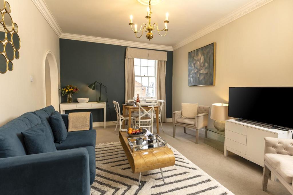 a living room with a blue couch and a tv at Wolcote House in Cheltenham