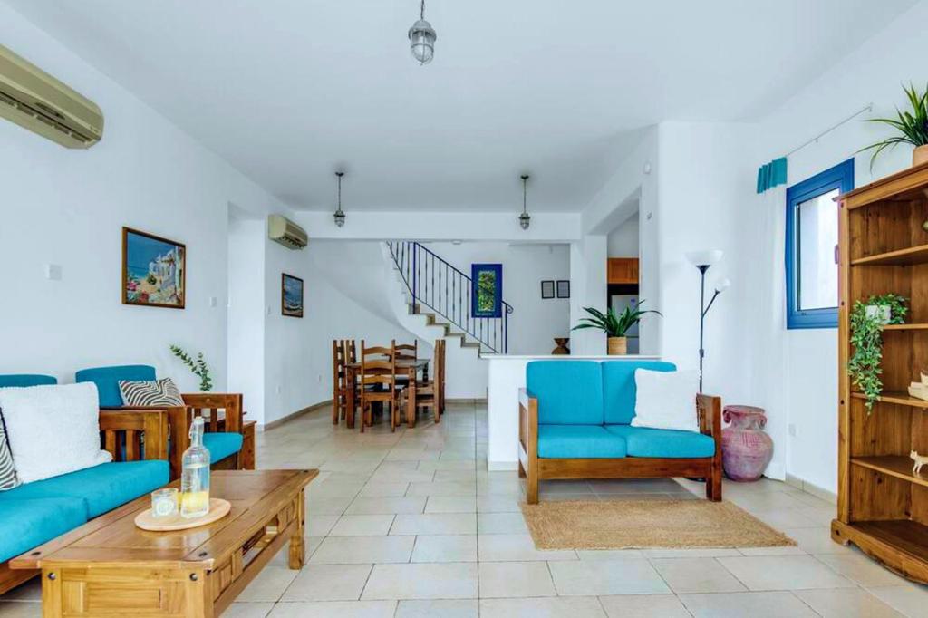 a living room with blue chairs and a table at Azzurro Holiday Villas in Peyia