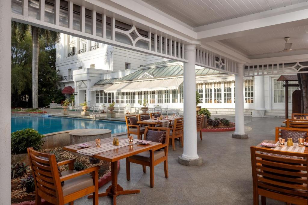 an outdoor patio with tables and chairs and a pool at ITC Windsor, a Luxury Collection Hotel, Bengaluru in Bengaluru
