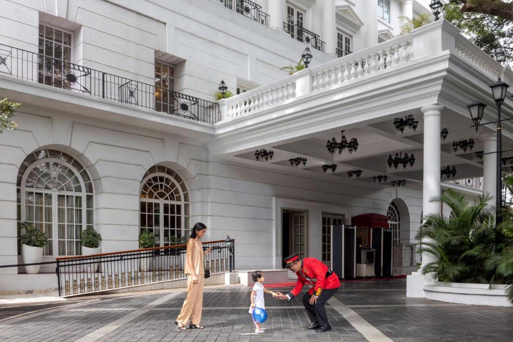a man and a woman and a child standing in front of a building at ITC Windsor, a Luxury Collection Hotel, Bengaluru in Bengaluru