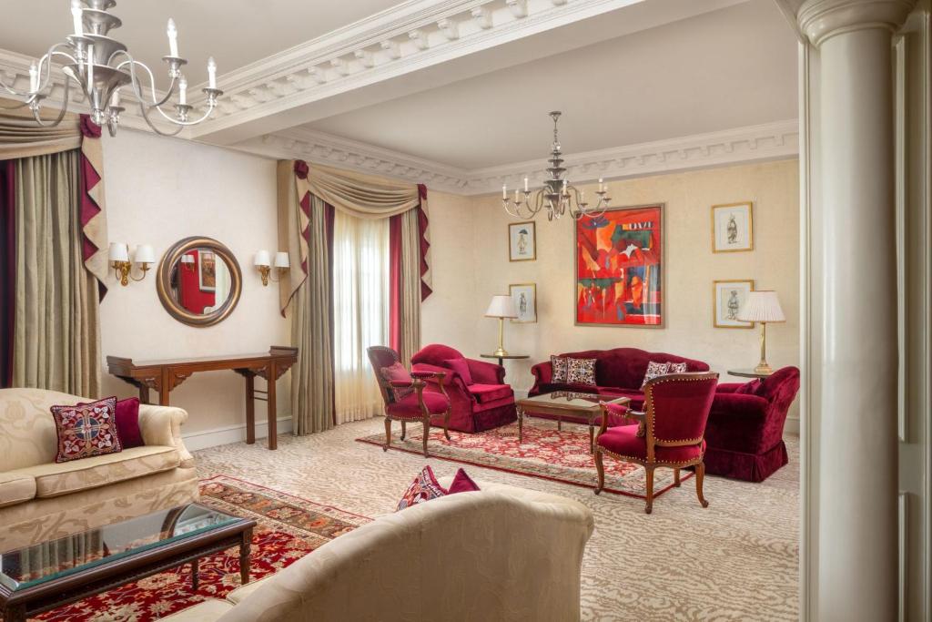 a living room with red chairs and a piano at ITC Windsor, a Luxury Collection Hotel, Bengaluru in Bengaluru