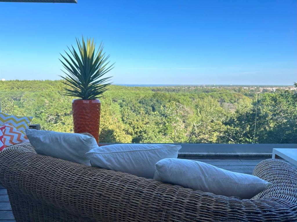 un canapé en osier assis sur une terrasse avec une plante en pot dans l'établissement Un havre de paix sur le Golf International d'Arcachon - vue imprenable, à La Teste-de-Buch