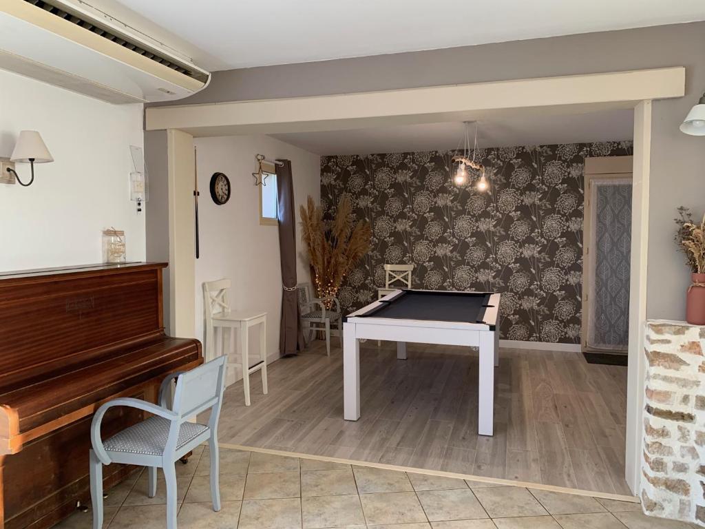 a living room with a piano and a table at Gite de Groupe Aux Instants Partagés in Fontenay-sur-Vègre
