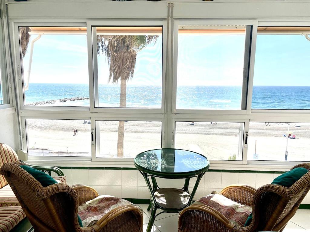 a table and chairs in a room with a view of the beach at Beachfront 75 in Torrox