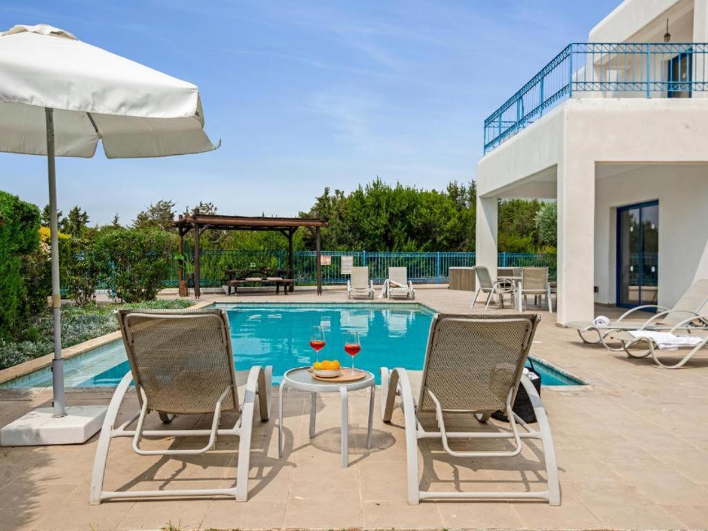 a pool with two chairs and a table and an umbrella at Azzurro Holiday Villas in Peyia