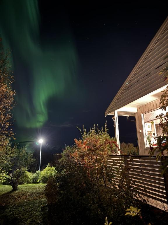 a house with a green aurora in the sky at Northstay - Tromsø Urban Escape, Modern House with 3 bedrooms, Free Parking in Tromsø