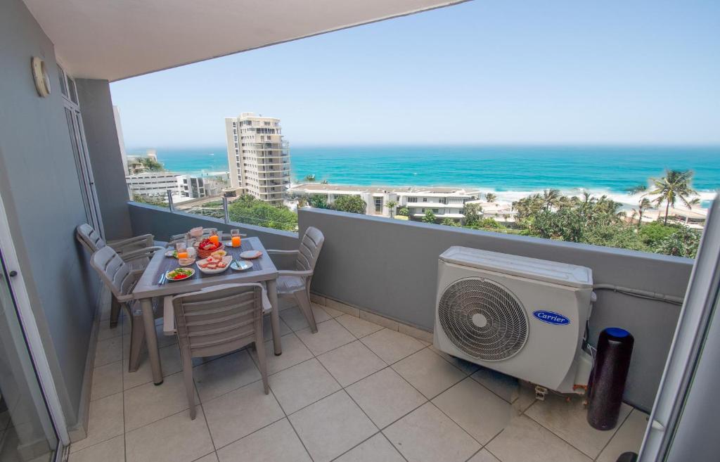 Un balcón con mesa y sillas y el mar. en 53 Sea Lodge Umhlanga Rocks, en Durban