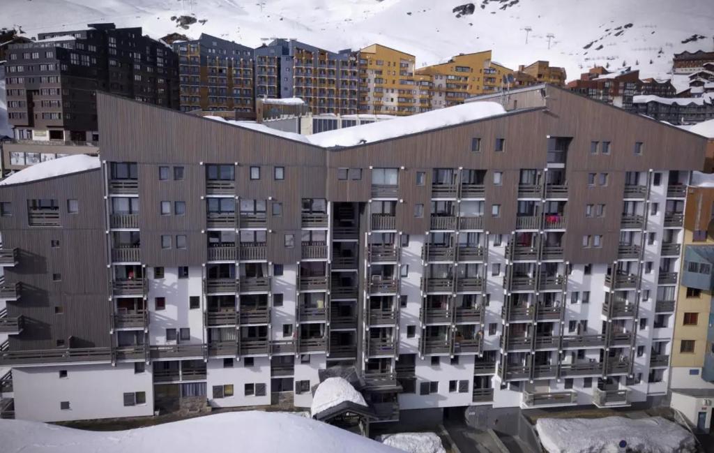 un edificio de apartamentos cubierto de nieve en una ciudad en Lauzier Nook by Alpstays, en Val Thorens