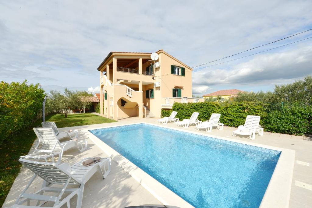 a villa with a swimming pool in front of a house at Villa Zvizda in Zadar