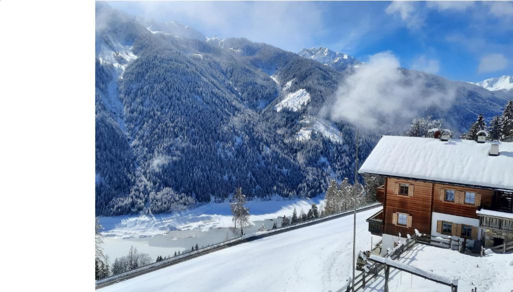 a house in the snow with a view of a mountain at Ferienwohnungen Kalchgruberhof in Ultimo
