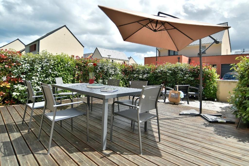 - une table avec des chaises et un parasol sur une terrasse dans l'établissement Lescale des douets fleuris, à Cancale