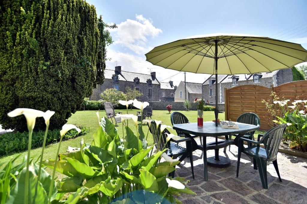 - une table et des chaises avec un parasol dans le jardin dans l'établissement Larmoricaine, à Cancale